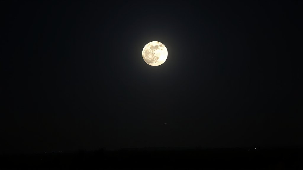 A high-resolution image of a supermoon in the night sky, with a few stars and a subtle meteor trail in the background, over a cityscape like Guwahati.