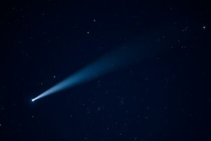 A high-resolution image of Comet Schaumasse passing a pair of globular clusters in the night sky, with a dark blue background and stars twinkling around it.