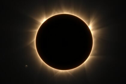 A stunning image of a total solar eclipse with a clear view of the sun's corona, taken from a unique location on Earth, with a subtle background of stars and planets.