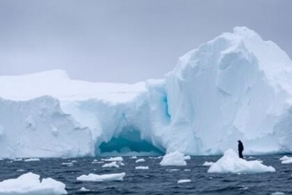A dramatic image of Antarctica's ice sheet collapsing, with massive chunks of ice breaking off into the ocean, and a subtle background of a researcher or scientist studying the phenomenon.