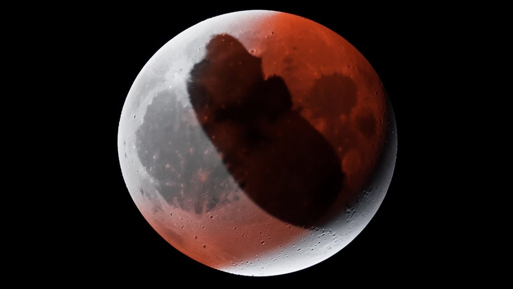 A high-quality image of a total lunar eclipse with the Earth's shadow visible on the moon's surface, including the moon's reddish hue during the eclipse.